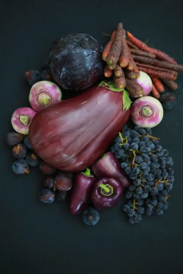 A colorful assortment of fruits and vegetables arranged on a black surface, showcasing their vibrant colors and textures.